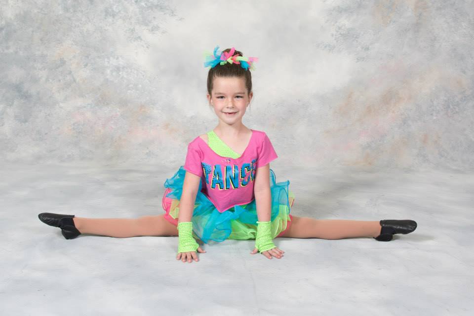 Young dancer performing perfect split in colorful dance costume